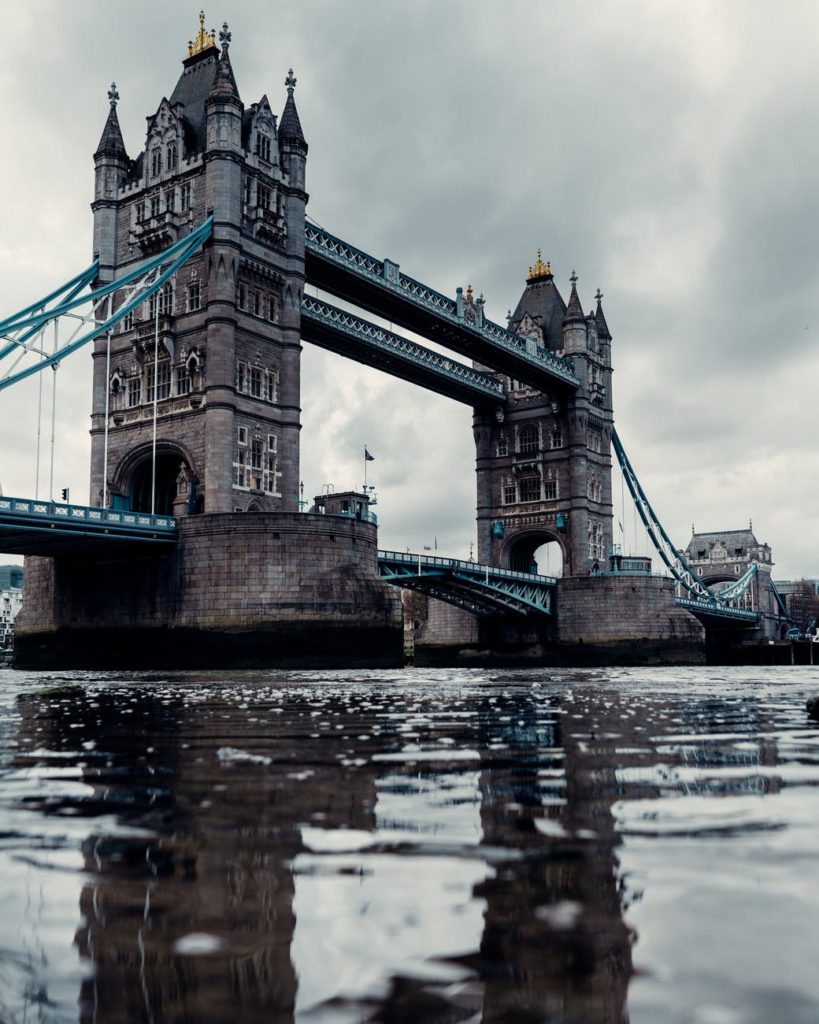 aged suspension bridge over river in city